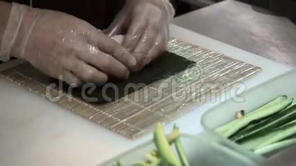 寿司卷的制作和切割过程男人用竹垫卷起寿司准备好的寿司卷视频的预览图