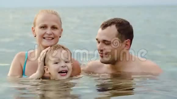可爱的家庭带着孩子在海里洗澡视频的预览图