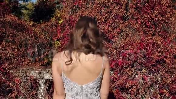 秋天一个穿着晚礼服的漂亮女孩走在一个废弃的公园里视频的预览图