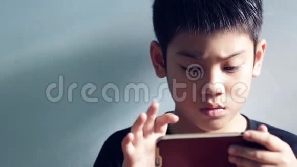 闭上小亚洲男孩玩耍和微笑坐在房间里倾斜相机视频的预览图