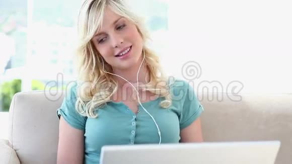 金发女人在笔记本电脑上听音乐视频的预览图