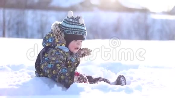 戴着冬帽的小男孩在雪地里玩耍视频的预览图