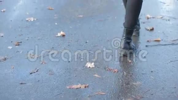 穿着黑色战靴的女孩在雨后的水坑里飞溅视频的预览图