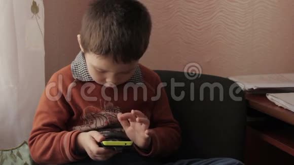Little男孩在你的智能手机上玩游戏视频的预览图