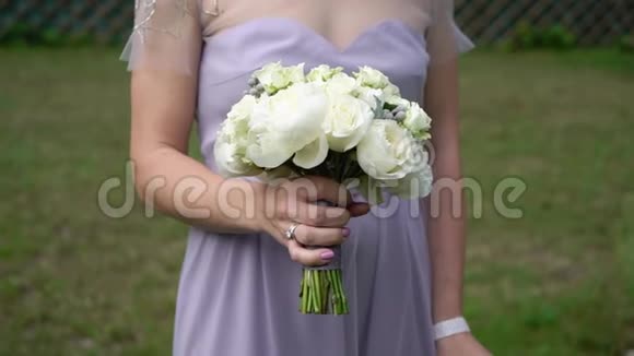 年轻的新娘穿着婚纱在公园里捧着花束白色豪华礼服视频的预览图