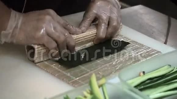 制作和切割橙色寿司卷的过程男人用竹垫卷起寿司准备好的寿司卷视频的预览图