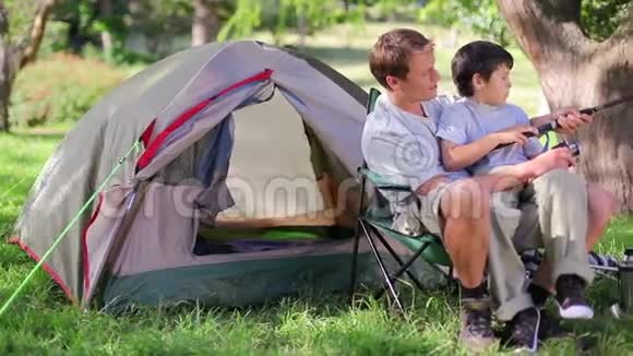 父子俩坐在帐篷附近钓鱼视频的预览图