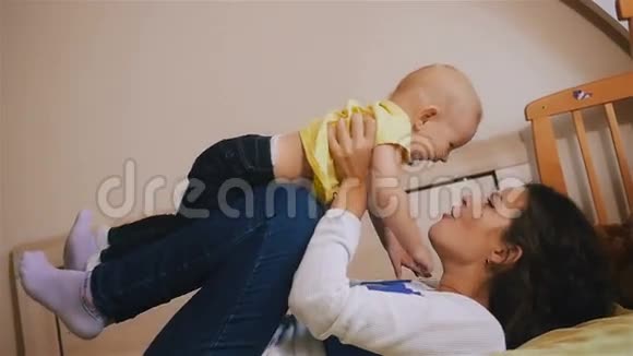 年轻的快乐母亲抱着她的新生儿吐了出来家里的家人美丽的微笑妈妈和快乐的宝贝视频的预览图