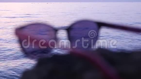 时尚的太阳镜躺在大海背景的石头上视频的预览图