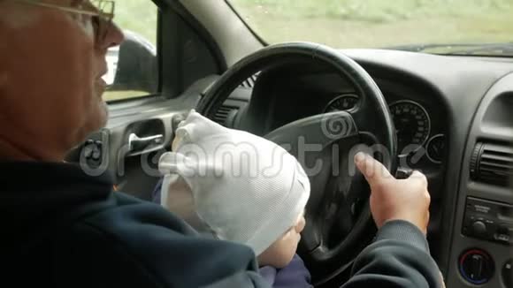 祖父在开车的时候和那个男孩玩孙子很高兴把不同的扣子拧了一下视频的预览图