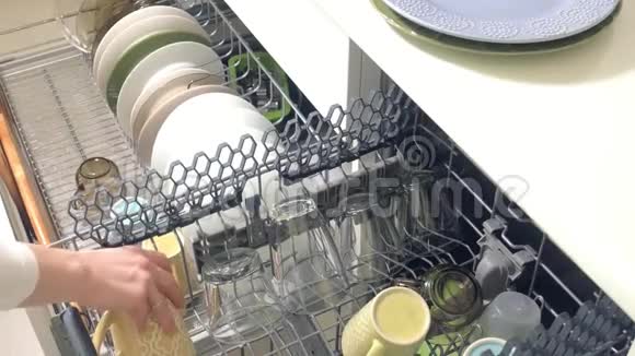 一个年轻的女人从洗碗机里拿出一个干净的盘子视频的预览图