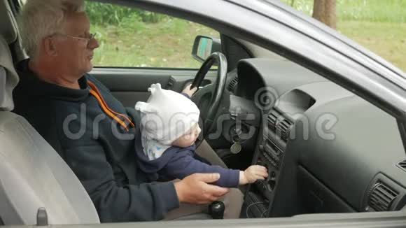 祖父在开车的时候和那个男孩玩孙子很高兴把不同的扣子拧了一下视频的预览图