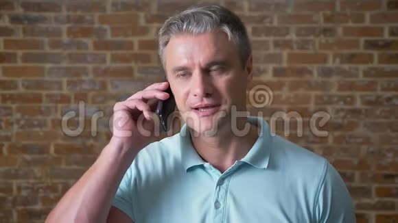 情感成熟的男人正在打电话认真地看着镜头离开时交谈站在那里视频的预览图