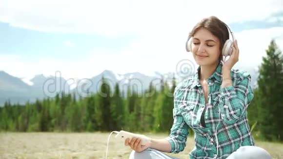 美丽的年轻女子带耳机户外喜欢音乐视频的预览图