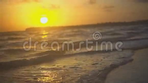 平静中的波浪在夕阳中轻轻地抚摸着海岸视频的预览图