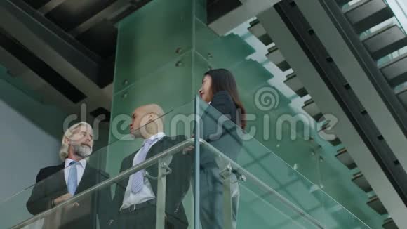 三个商业人士站在现代办公大楼里交谈视频的预览图