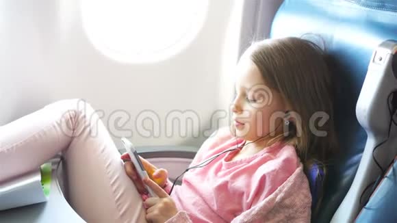 可爱的小女孩乘飞机旅行飞机窗户附近有笔记本电脑的可爱孩子视频的预览图