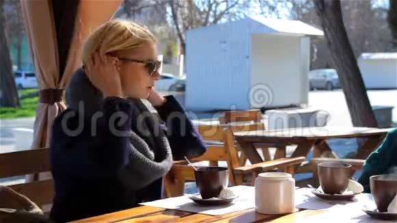 三个迷人的年轻女孩坐在户外咖啡馆里聊天视频的预览图