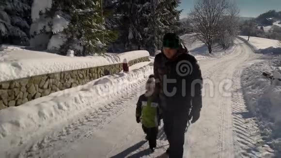 年轻的幸福家庭在雪林里玩得很开心父亲把他的小儿子卷在雪橇上爸爸和他的小儿子视频的预览图
