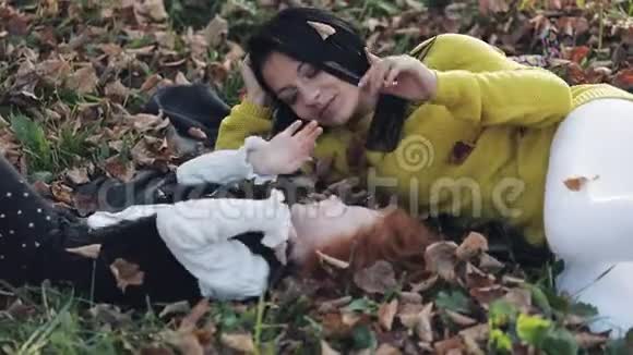 快乐的年轻母亲和她的小红发女儿在秋天的公园里玩得很开心他们玩着笑着慢动作视频的预览图
