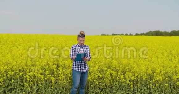 油菜田剪贴板上自信的女农民写作视频的预览图