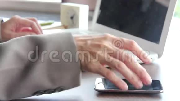 办公室里有智能手机和笔记本电脑的女商人视频的预览图