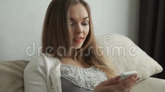 家庭技术和互联网概念微笑的女人坐在沙发上家里有智能手机视频的预览图