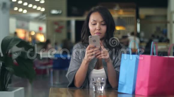 妇女在商场购物后使用手机视频的预览图
