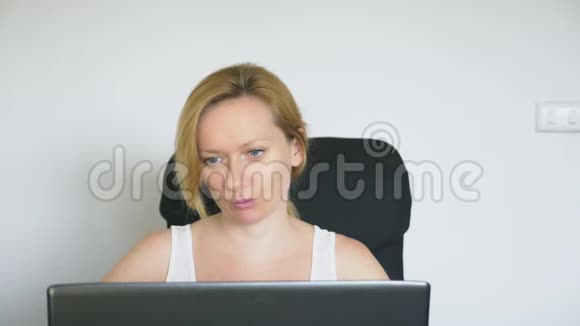一个女人用她的笔记本电脑坐在桌子旁笑着说话人类的情感网瘾视频的预览图
