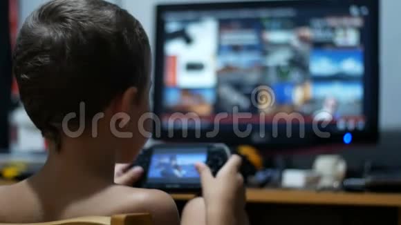 儿童正在玩便携式游戏控制台坐在家里的椅子上视频的预览图