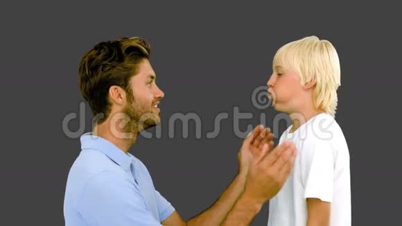 男人用灰色背景压着儿子鼓鼓的脸颊视频的预览图