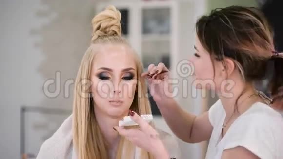 专业美容师和设计师在工作对于一个壮观的顶级模特做一个明亮富有表现力的化妆时尚视频的预览图