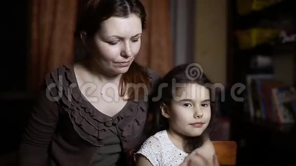 母亲和女儿拥抱在家庭房间晚上的生活方式视频的预览图