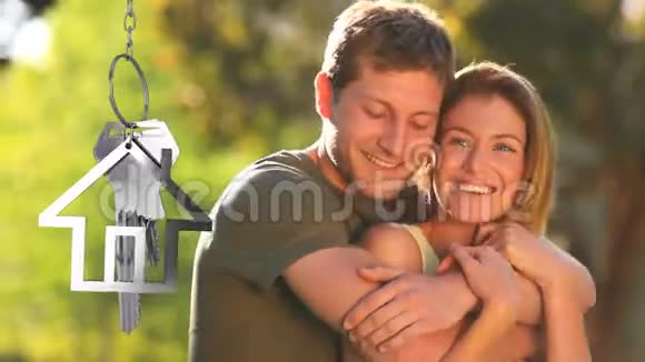 房子钥匙和钥匙挂在背景中带着微笑的情侣视频的预览图