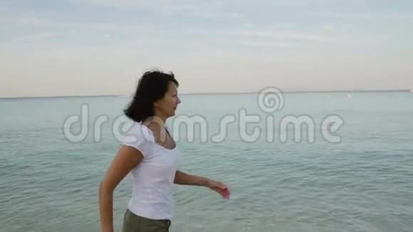 日出时光着脚在沙滩上奔跑的女人视频的预览图