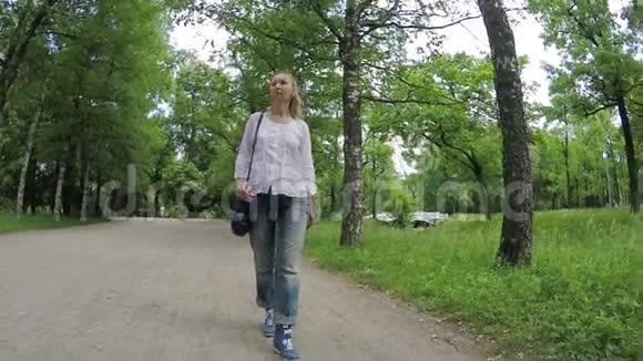 这位美丽的女人在绿色的路上走着视频的预览图