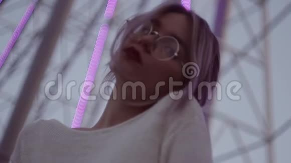 有魅力的年轻女子戴着圆形眼镜带着马尾辫在游乐园视频的预览图