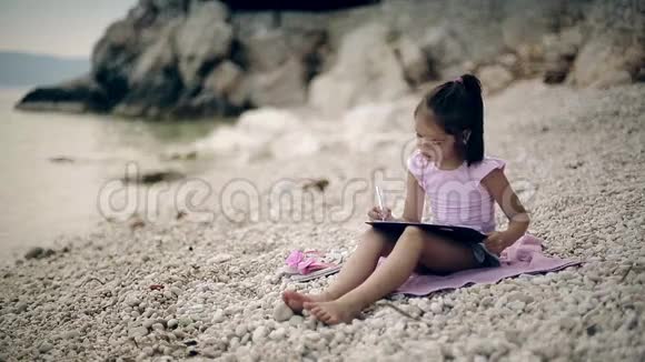 一个孩子坐在亚得里亚海附近的石头上画了一幅画中弹视频的预览图