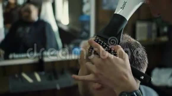 新发型在坐在椅子上的时候年轻的胡须男用吹风机在理发店洗头发视频的预览图