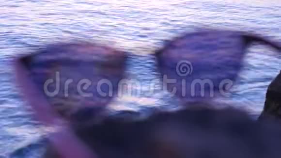 时尚的太阳镜躺在大海背景的石头上视频的预览图