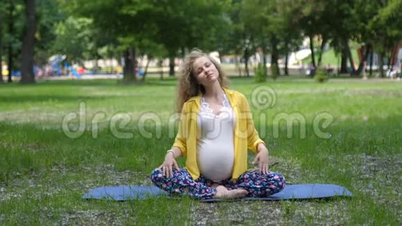 美丽的孕妇在户外做产前瑜伽怀孕期间的运动健身和健康生活方式视频的预览图