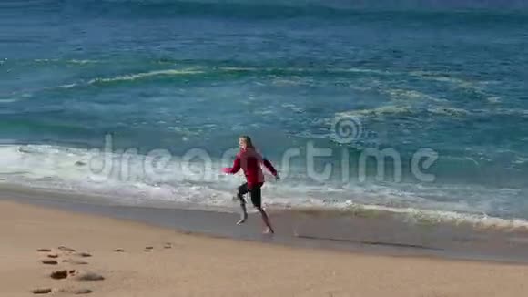 女人用波浪在海滩上奔跑视频的预览图