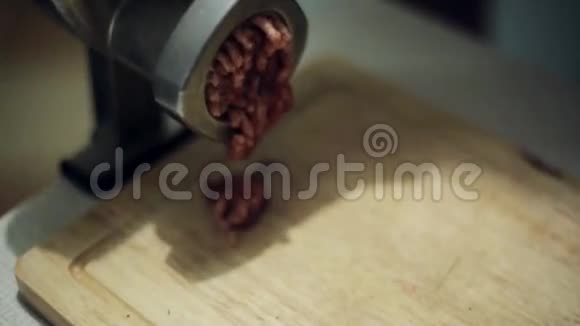 用铝制绞肉机在木质厨房板上研磨鲜肉的过程视频的预览图