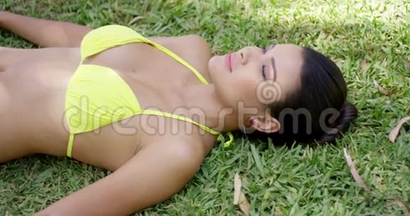 微笑着躺在草地上的年轻女人视频的预览图