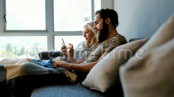 一对夫妇在4k的客厅里使用手机和笔记本电脑视频的预览图
