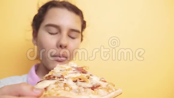 快乐的小女孩吃一片披萨的概念十几岁的孩子饿了吃一片披萨慢动作录像披萨视频的预览图