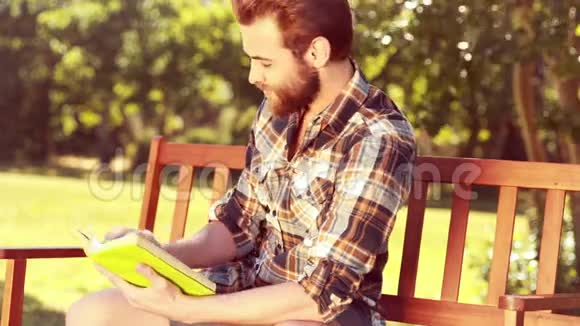 在公园里高质量的4k格式英俊的嬉皮士阅读视频的预览图