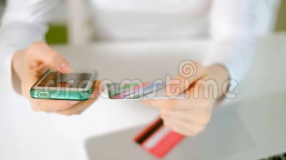 一位年轻女子在网上商店买东西并通过手机支付信用卡视频的预览图