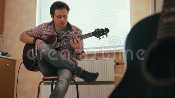 年轻人用吉他作曲在厨房里演奏其他乐器在前台视频的预览图