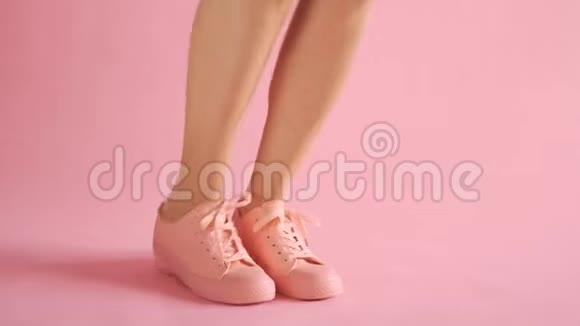 在珊瑚色背景下穿着运动鞋跳舞的苗条女性腿视频的预览图